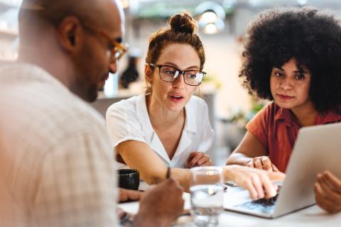 three people looking at laptop